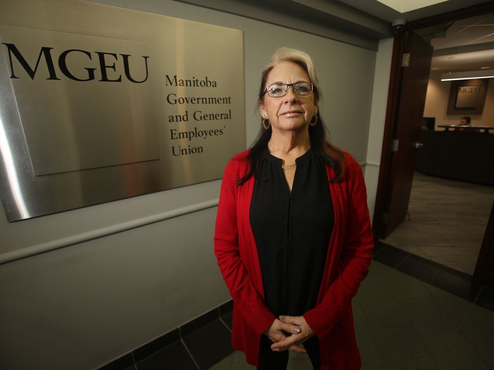 Michelle Gawronsky standing in front of a plaque for the Manitoba Government and General Employees’ Union, hands clasped